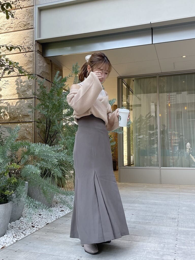 ベージュ系のニット/セーター、ベージュ系のスカート、ベージュ系のブーツを着用したレディースの秋コーディネートの2枚目の写真