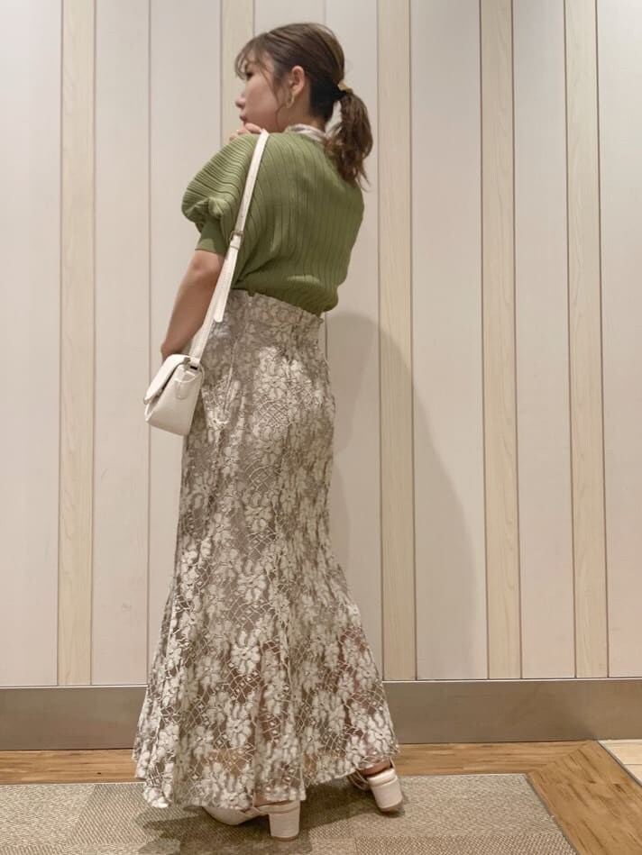 ベージュ系のスカート、ホワイト系のパンプス、グリーン系のニット/セーターを着用したレディースの春コーディネートの3枚目の写真