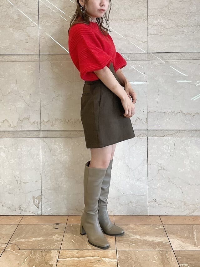 レッド系のニット/セーター、ブラウン系のスカート、ベージュ系のブーツを着用したレディースの秋コーディネートの3枚目の写真