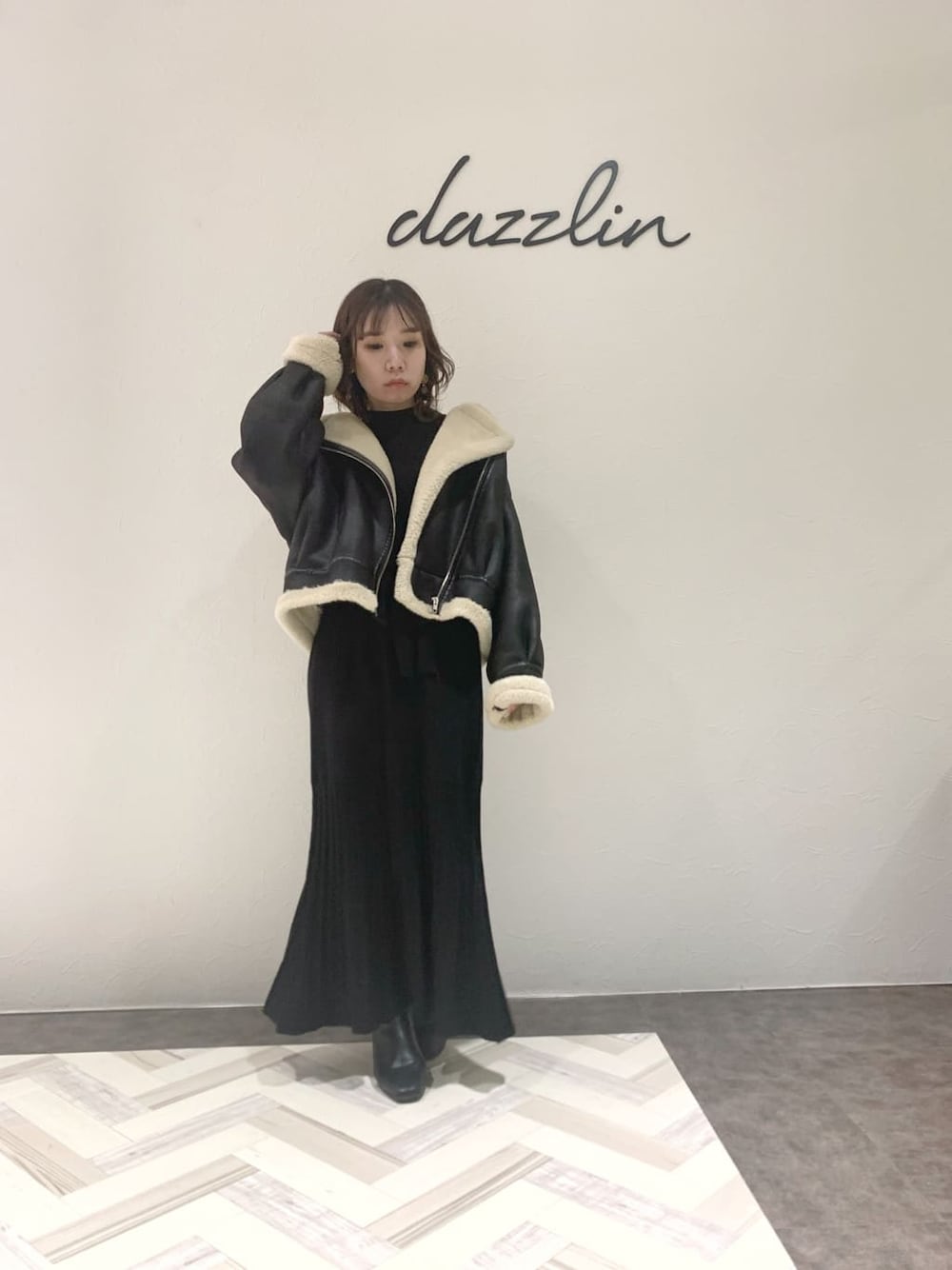 ブラック系のブルゾン、ブラック系のワンピース、ブラック系のブーツを着用したレディースの秋コーディネートの2枚目の写真