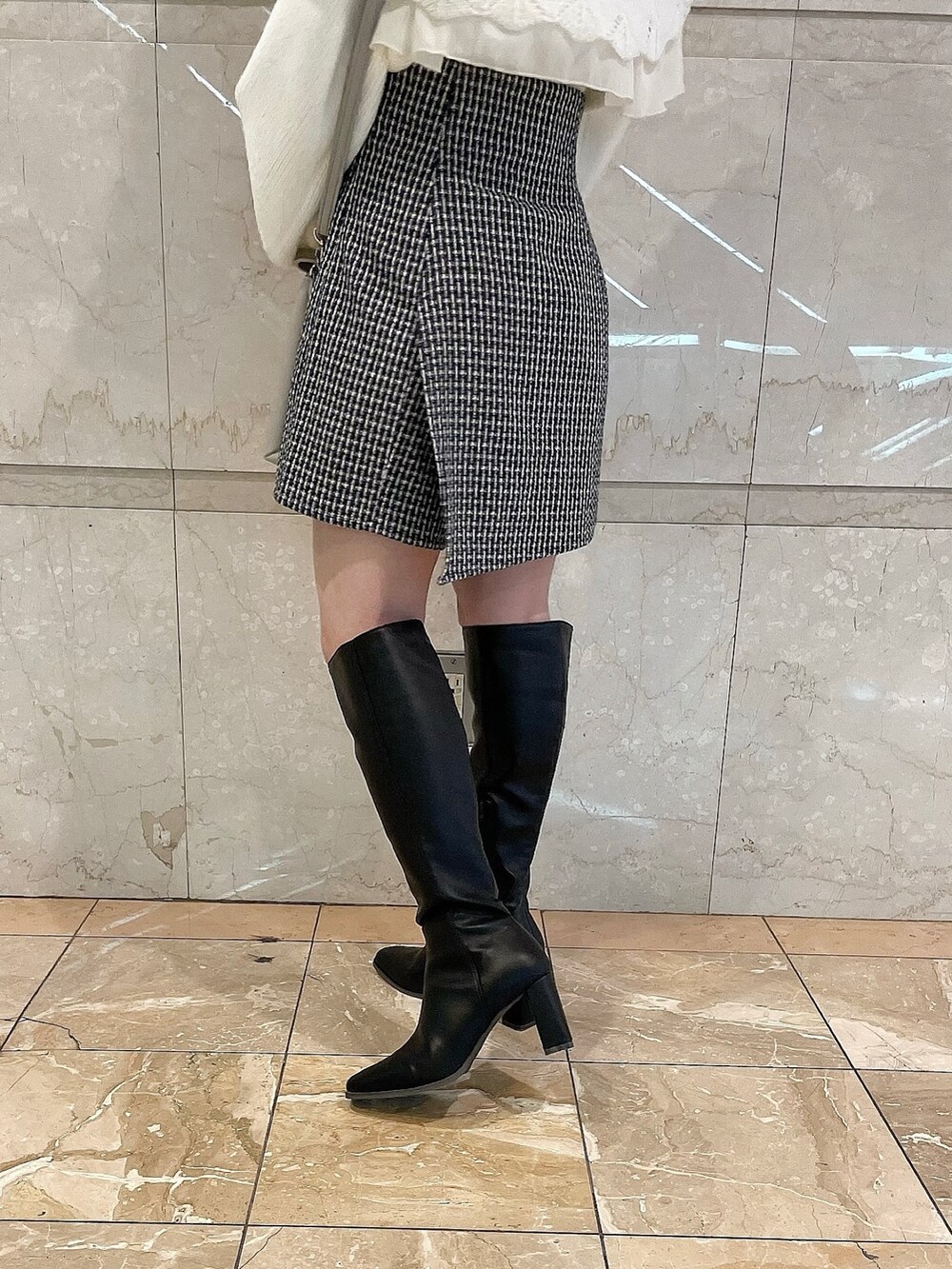 ホワイト系のニット/セーター、ブルー系のスカート、ブラック系のブーツを着用したレディースの秋コーディネートの10枚目の写真