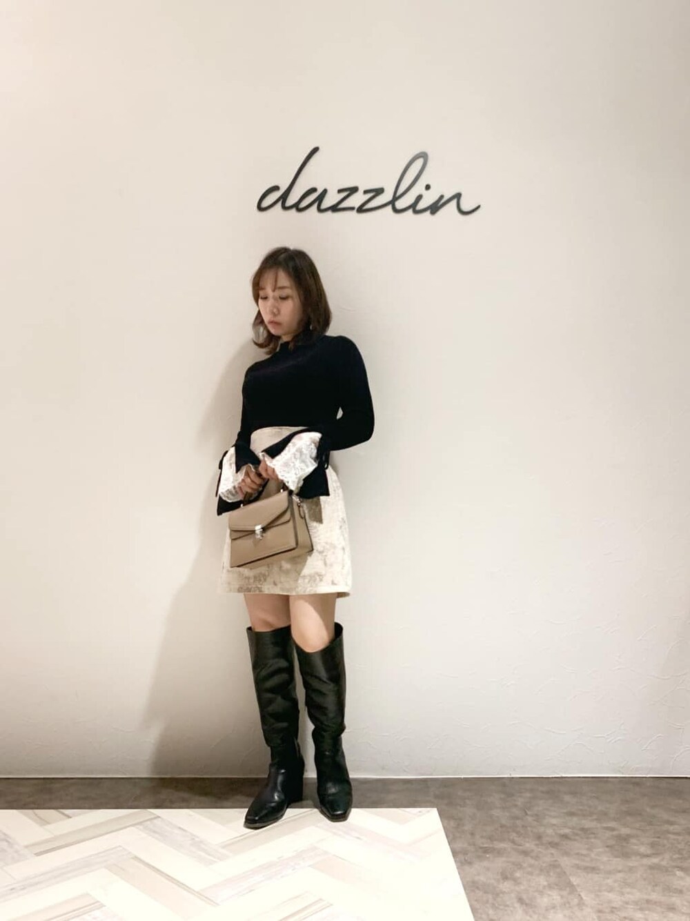 ベージュ系のスカート、ブラック系のブーツ、ブラック系のニット/セーターを着用したレディースの秋コーディネートの2枚目の写真