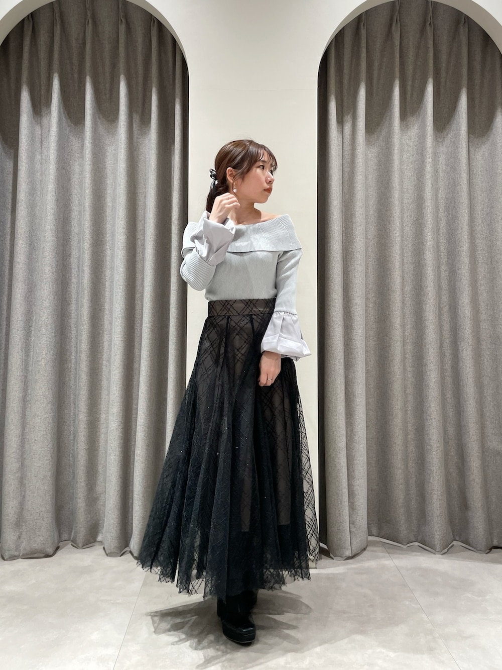 ブラック系のスカート、グレー系のニット/セーター、ブラック系のブーツを着用したレディースの春コーディネートの5枚目の写真