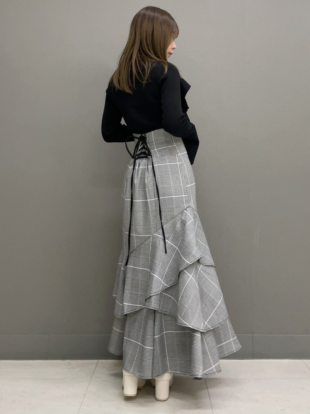 ホワイト系のブーツ、ブラック系のニット/セーター、その他のスカートを着用したレディースの秋コーディネートの5枚目の写真