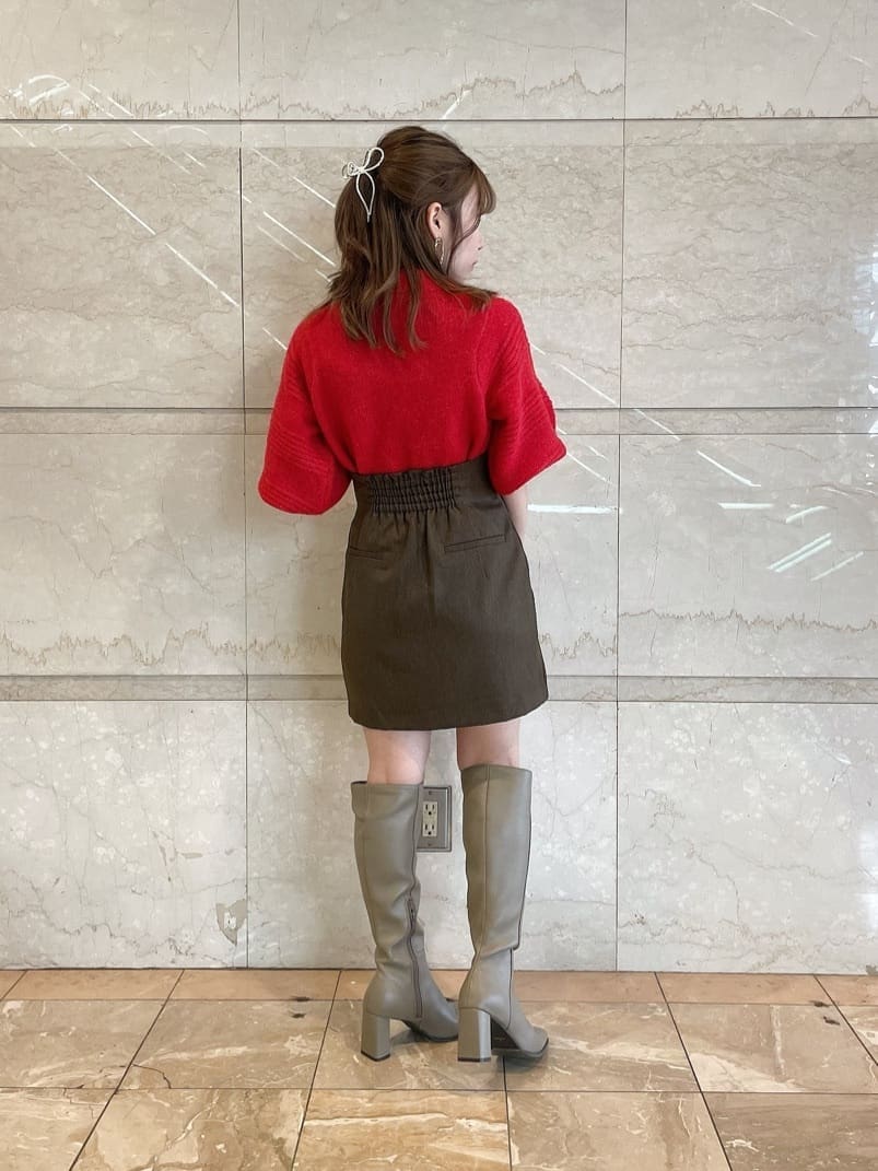 レッド系のニット/セーター、ブラウン系のスカート、ベージュ系のブーツを着用したレディースの秋コーディネートの5枚目の写真