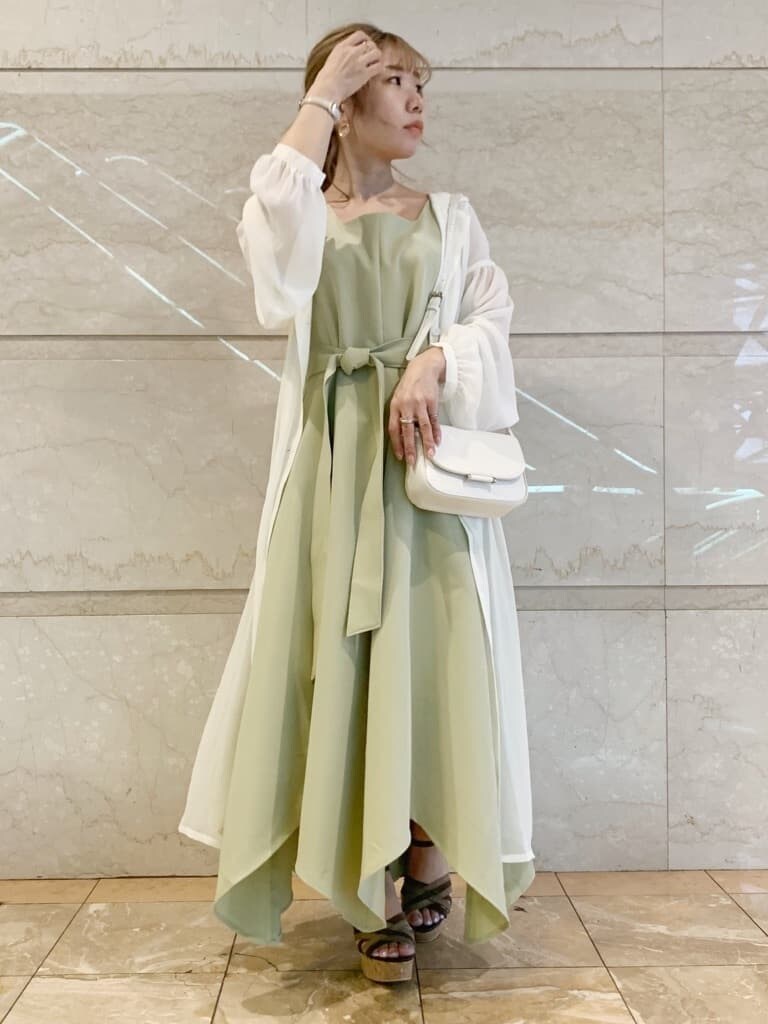 グリーン系のワンピース、ブラウン系のサンダル、ホワイト系のシャツ/ブラウスを着用したレディースの春コーディネートの6枚目の写真