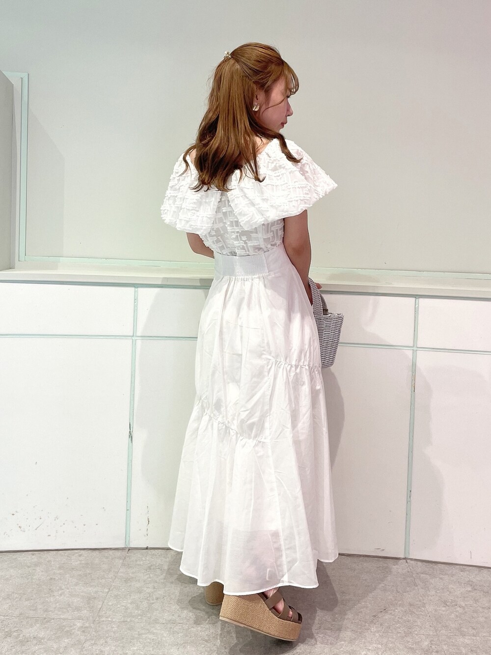 ホワイト系のシャツ/ブラウス、ホワイト系のスカート、ブラウン系のサンダルを着用したレディースの夏コーディネートの3枚目の写真