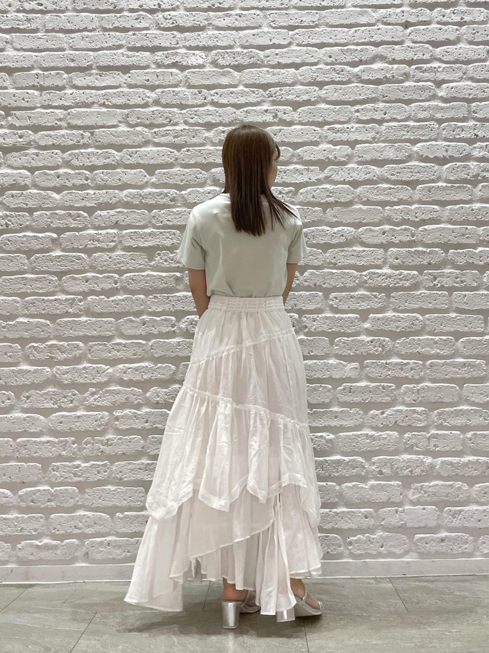 グリーン系のTシャツ/カットソー、ホワイト系のスカート、シルバー系のパンプスを着用したレディースの春コーディネートの4枚目の写真