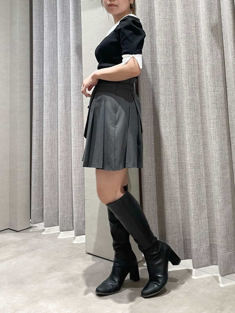 ブラック系のニット/セーター、グレー系のスカート、ブラック系のブーツを着用したレディースの春コーディネートの3枚目の写真