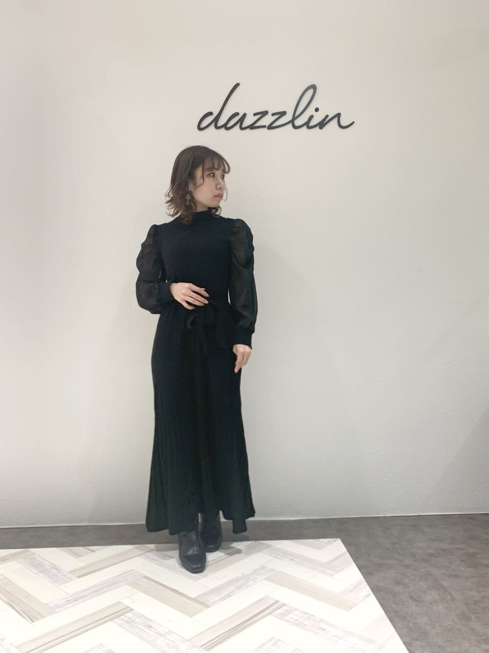 ブラック系のブルゾン、ブラック系のワンピース、ブラック系のブーツを着用したレディースの秋コーディネートの4枚目の写真