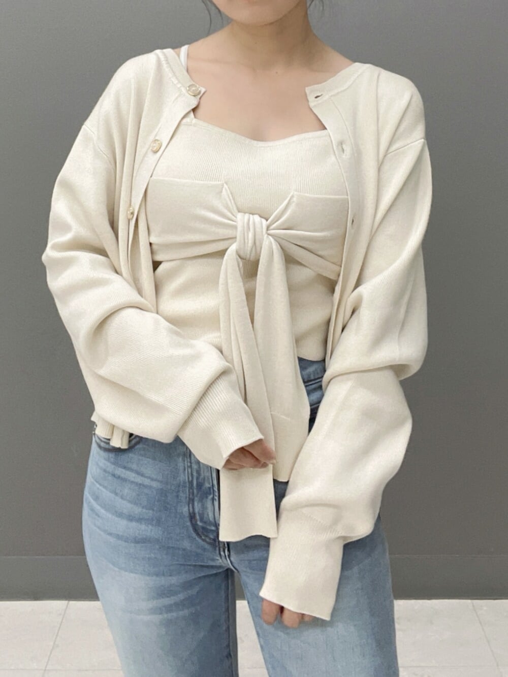 ホワイト系のキャミソール、ホワイト系のカーディガン/ボレロ、ブルー系のデニムパンツを着用したレディースの秋コーディネートの5枚目の写真