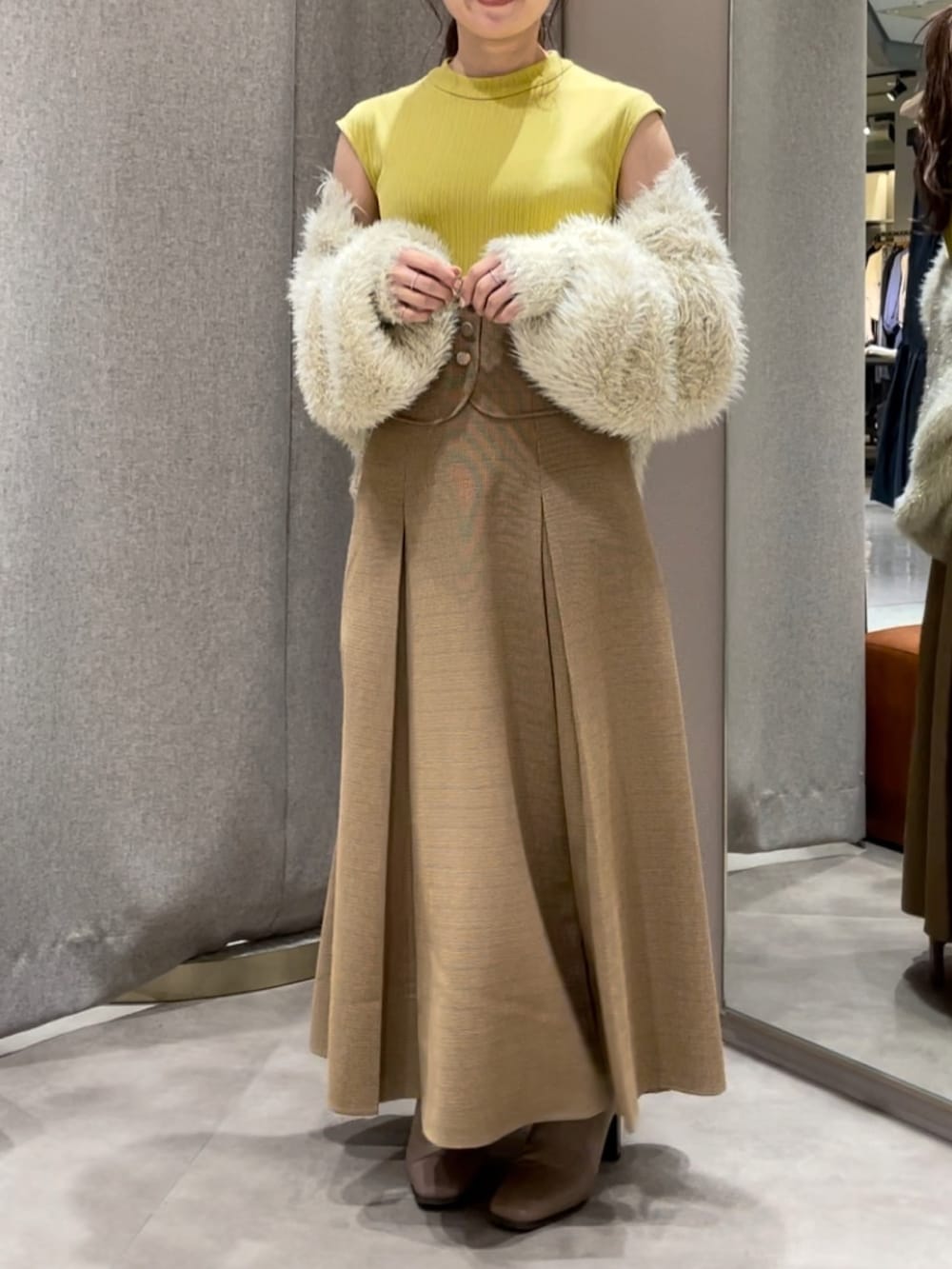 ベージュ系のカーディガン/ボレロ、イエロー系のワンピース、ベージュ系のブーツを着用したレディースの秋コーディネートの3枚目の写真