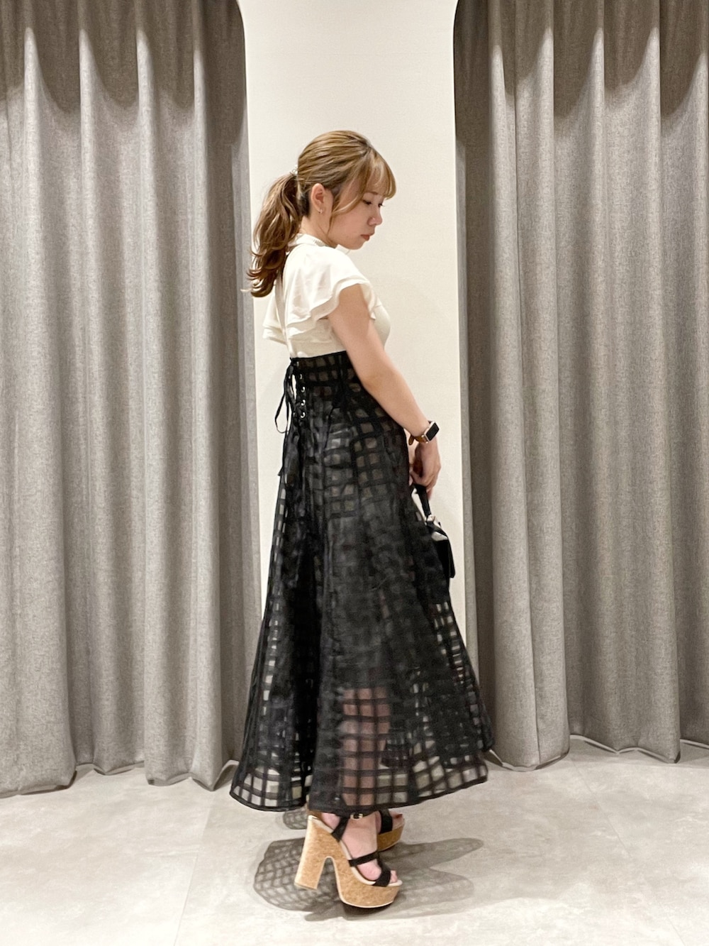 ホワイト系のワンピース、ブラック系のハンドバッグ、ブラック系のサンダルを着用したレディースの夏コーディネートの3枚目の写真