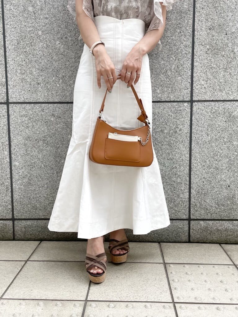 ホワイト系のスカート、ブラウン系のハンドバッグ、ブラウン系のサンダルを着用したレディースの夏コーディネートの6枚目の写真