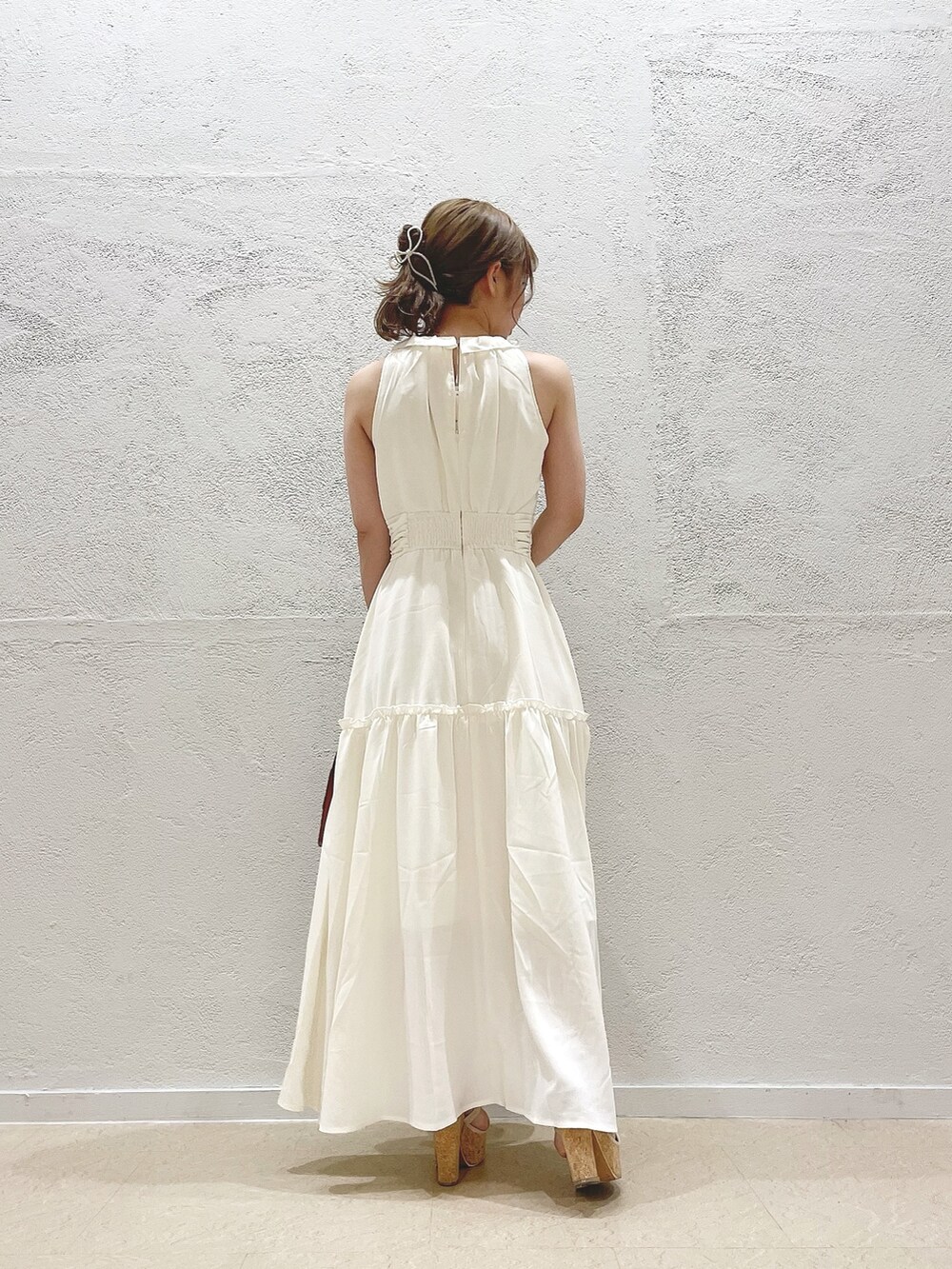 イエロー系のハンドバッグ、ホワイト系のサンダル、ホワイト系のワンピースを着用したレディースの夏コーディネートの3枚目の写真