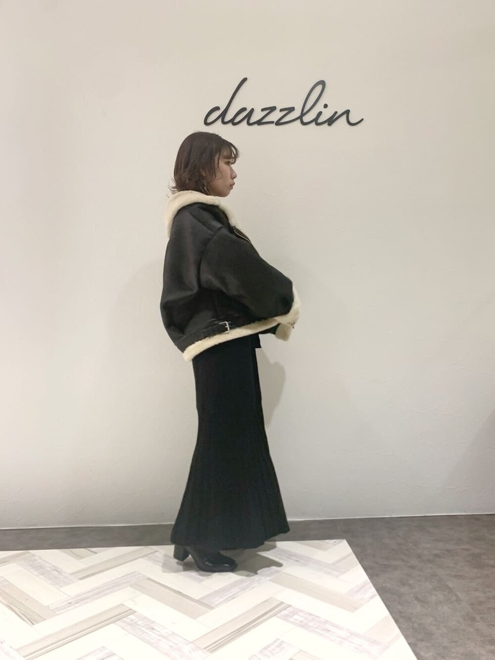 ブラック系のブルゾン、ブラック系のワンピース、ブラック系のブーツを着用したレディースの秋コーディネートの3枚目の写真