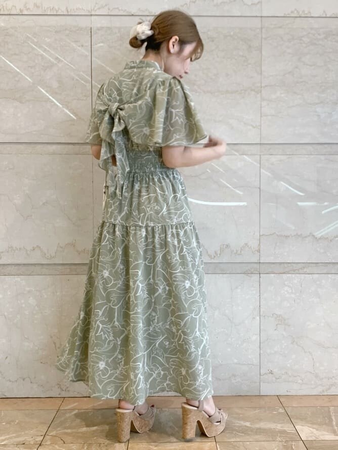 グリーン系のワンピース、ベージュ系のサンダル、ホワイト系のショルダーバッグを着用したレディースの春コーディネートの2枚目の写真