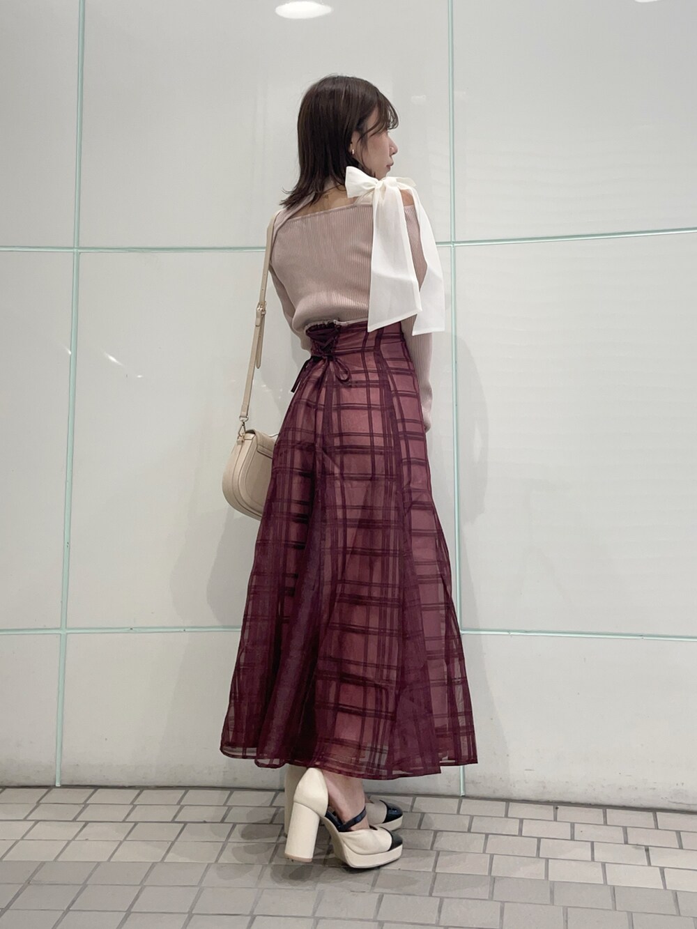 ピンク系のニット/セーター、レッド系のスカート、ホワイト系のハンドバッグを着用したレディースの秋コーディネートの2枚目の写真