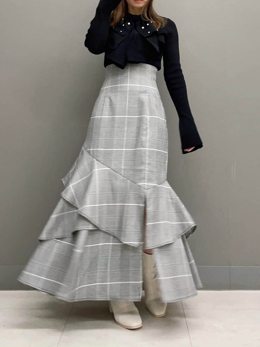 ホワイト系のブーツ、ブラック系のニット/セーター、その他のスカートを着用したレディースの秋コーディネートの4枚目の写真