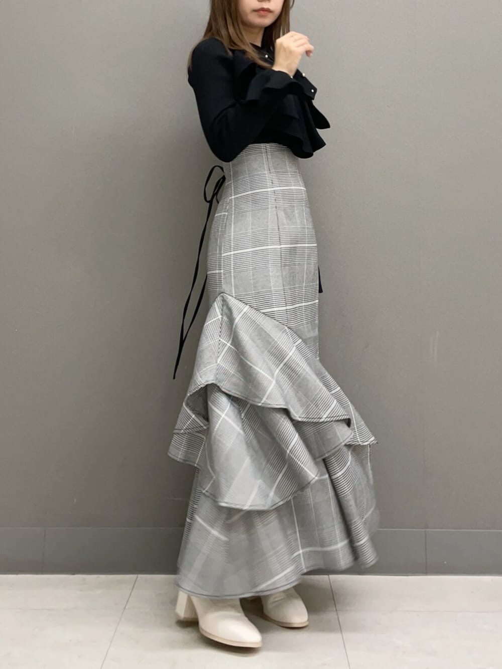 ホワイト系のブーツ、ブラック系のニット/セーター、その他のスカートを着用したレディースの秋コーディネートの6枚目の写真