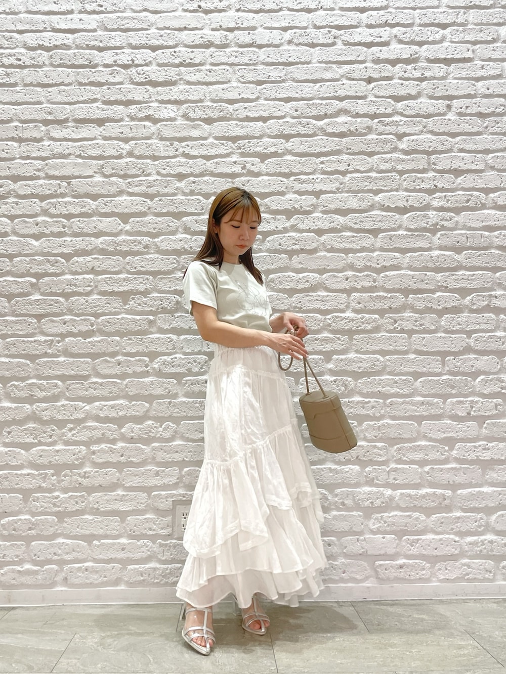 グリーン系のTシャツ/カットソー、ホワイト系のスカート、シルバー系のパンプスを着用したレディースの春コーディネートの3枚目の写真