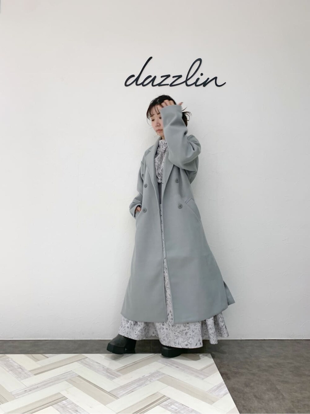 グレー系のブーツ、ブルー系のチェスターコート、グレー系のワンピースを着用したレディースの冬コーディネートの2枚目の写真