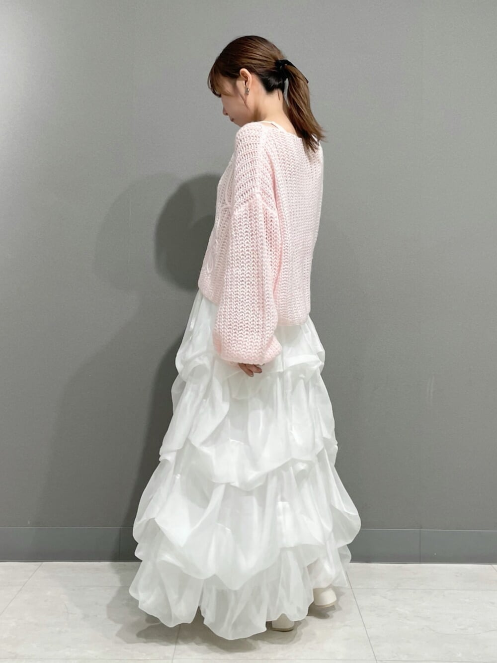 ピンク系のニット/セーター、ホワイト系のスカート、ホワイト系のブーツを着用したレディースの秋コーディネートの5枚目の写真