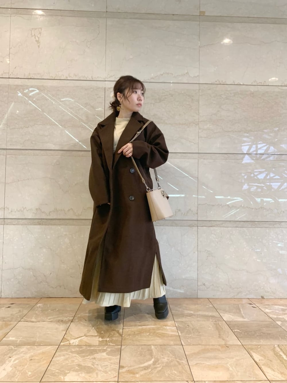 ブラック系のブーツ、ブラウン系のチェスターコート、ベージュ系のワンピースを着用したレディースの冬コーディネートの5枚目の写真