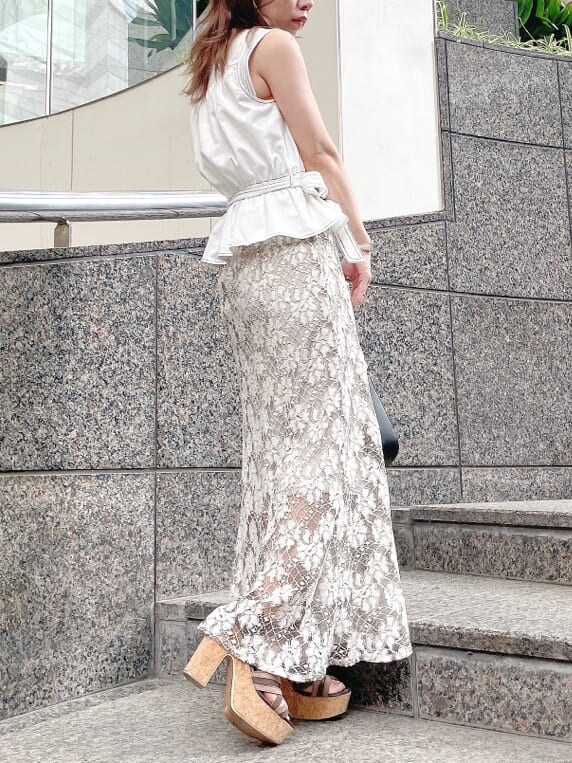 ベージュ系のスカート、ブラウン系のサンダル、ホワイト系のシャツ/ブラウスを着用したレディースの夏コーディネートの2枚目の写真