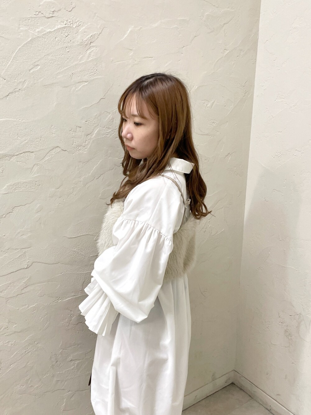 ホワイト系のワンピース、ベージュ系のベスト、イエロー系のハンドバッグを着用したレディースの夏コーディネートの6枚目の写真