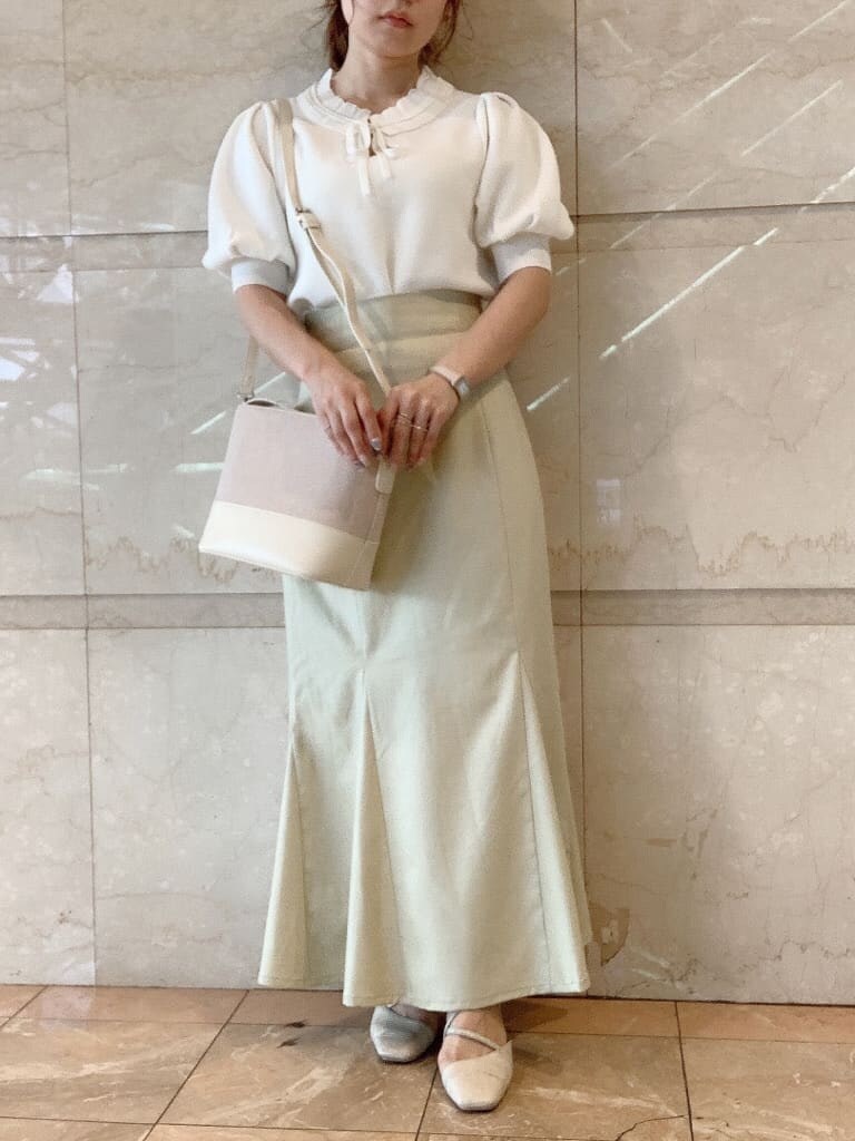 グリーン系のスカート、ホワイト系のパンプス、ホワイト系のハンドバッグを着用したレディースの春コーディネートの4枚目の写真