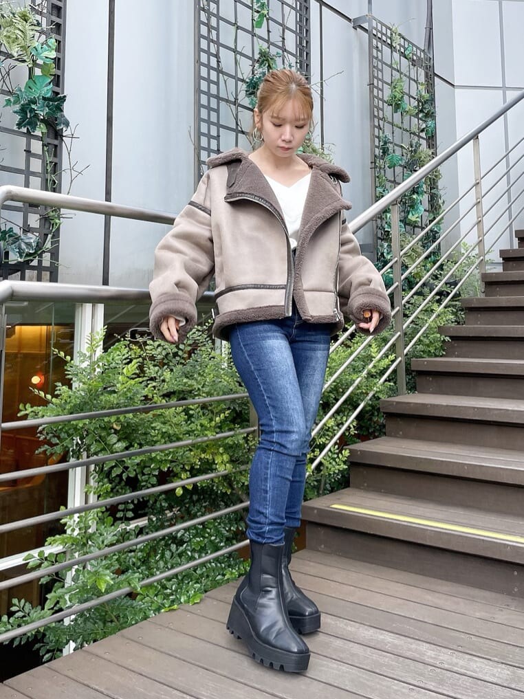 ブルー系のデニムパンツ、ホワイト系のニット/セーター、ブルー系のデニムパンツを着用したレディースの秋コーディネートの3枚目の写真