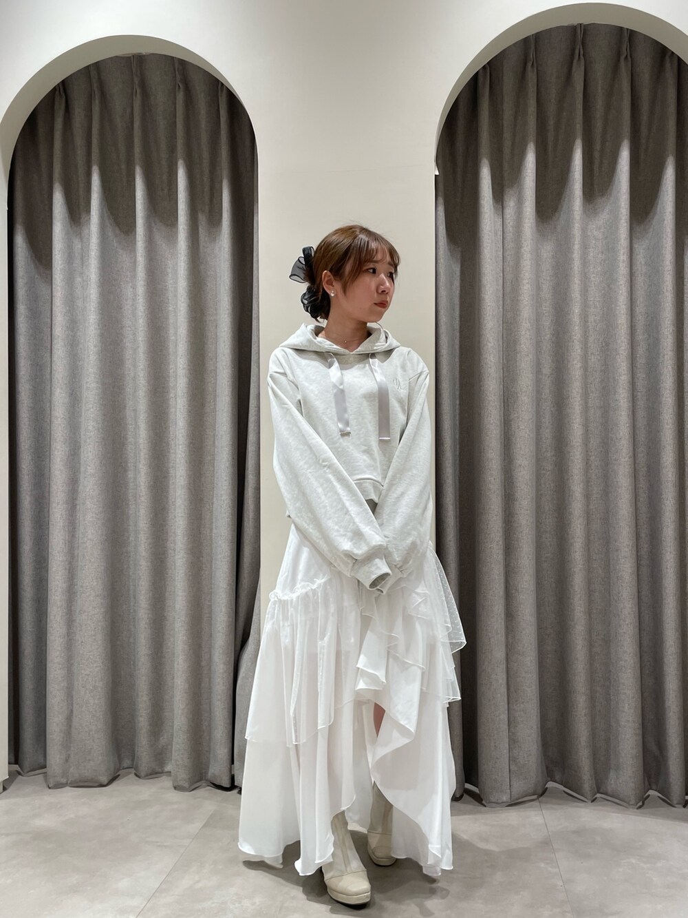 グレー系のパーカー、ホワイト系のスカート、ホワイト系のブーツを着用したレディースの春コーディネートの5枚目の写真