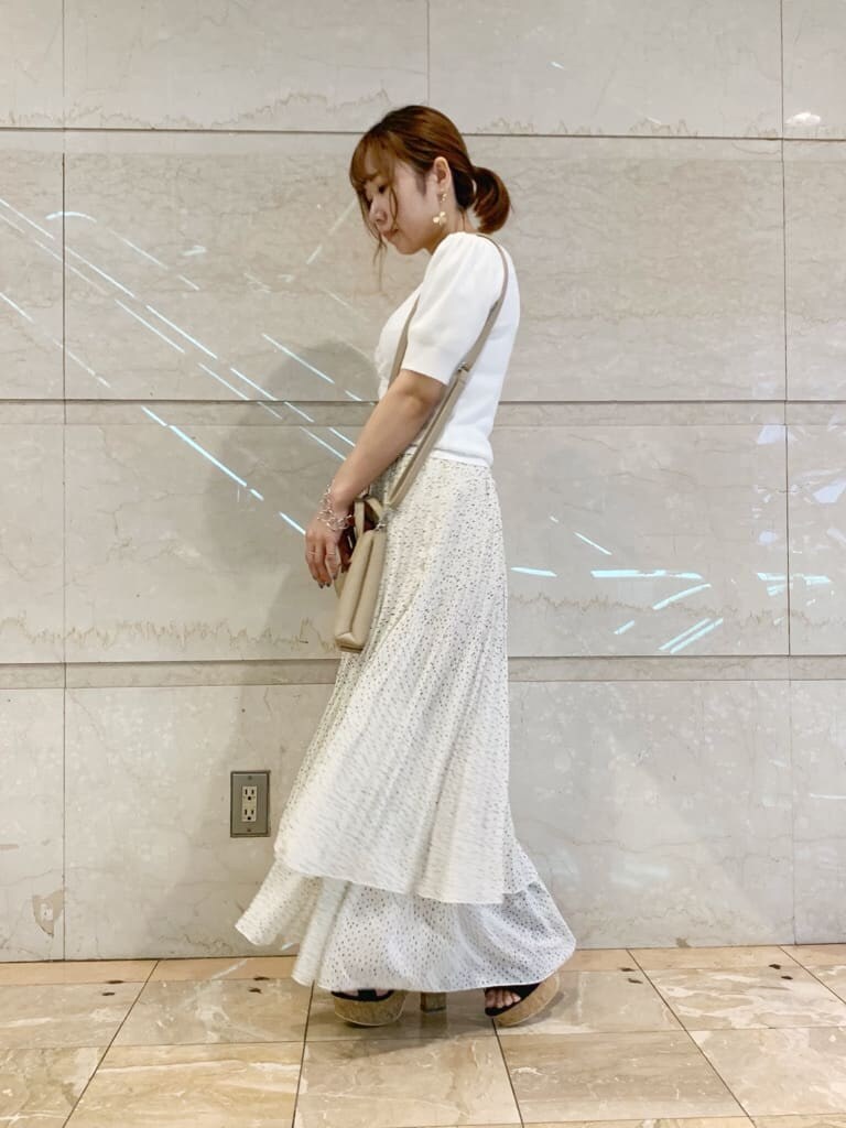 ブラック系のサンダル、ベージュ系のハンドバッグ、ホワイト系のニット/セーターを着用したレディースの夏コーディネートの3枚目の写真