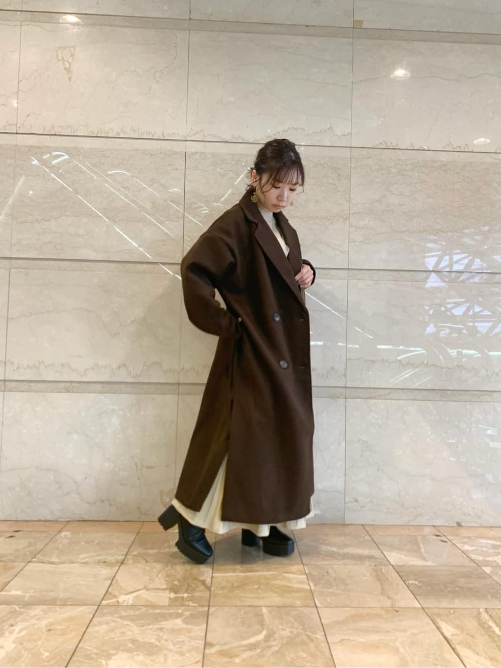 ブラック系のブーツ、ブラウン系のチェスターコート、ベージュ系のワンピースを着用したレディースの冬コーディネートの9枚目の写真