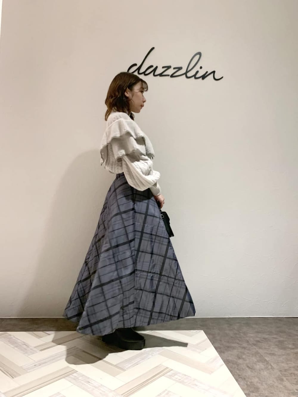 ブラック系のハンドバッグ、グレー系のスカート、グレー系のブーツを着用したレディースの秋コーディネートの2枚目の写真