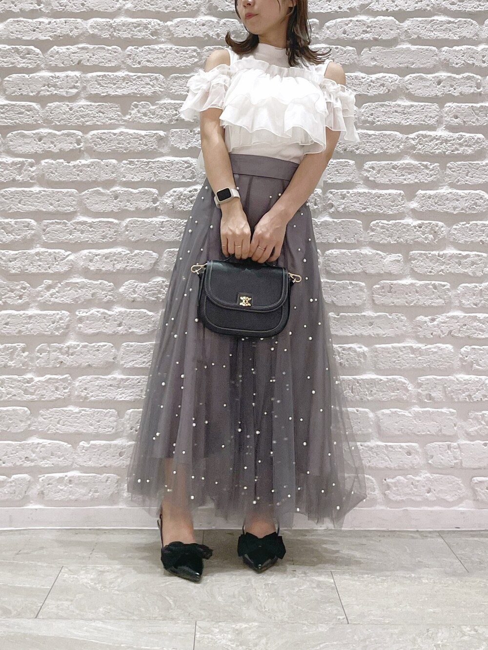 ホワイト系のTシャツ/カットソー、ブラック系のパンプス、ブラック系のハンドバッグを着用したレディースの夏コーディネートの4枚目の写真