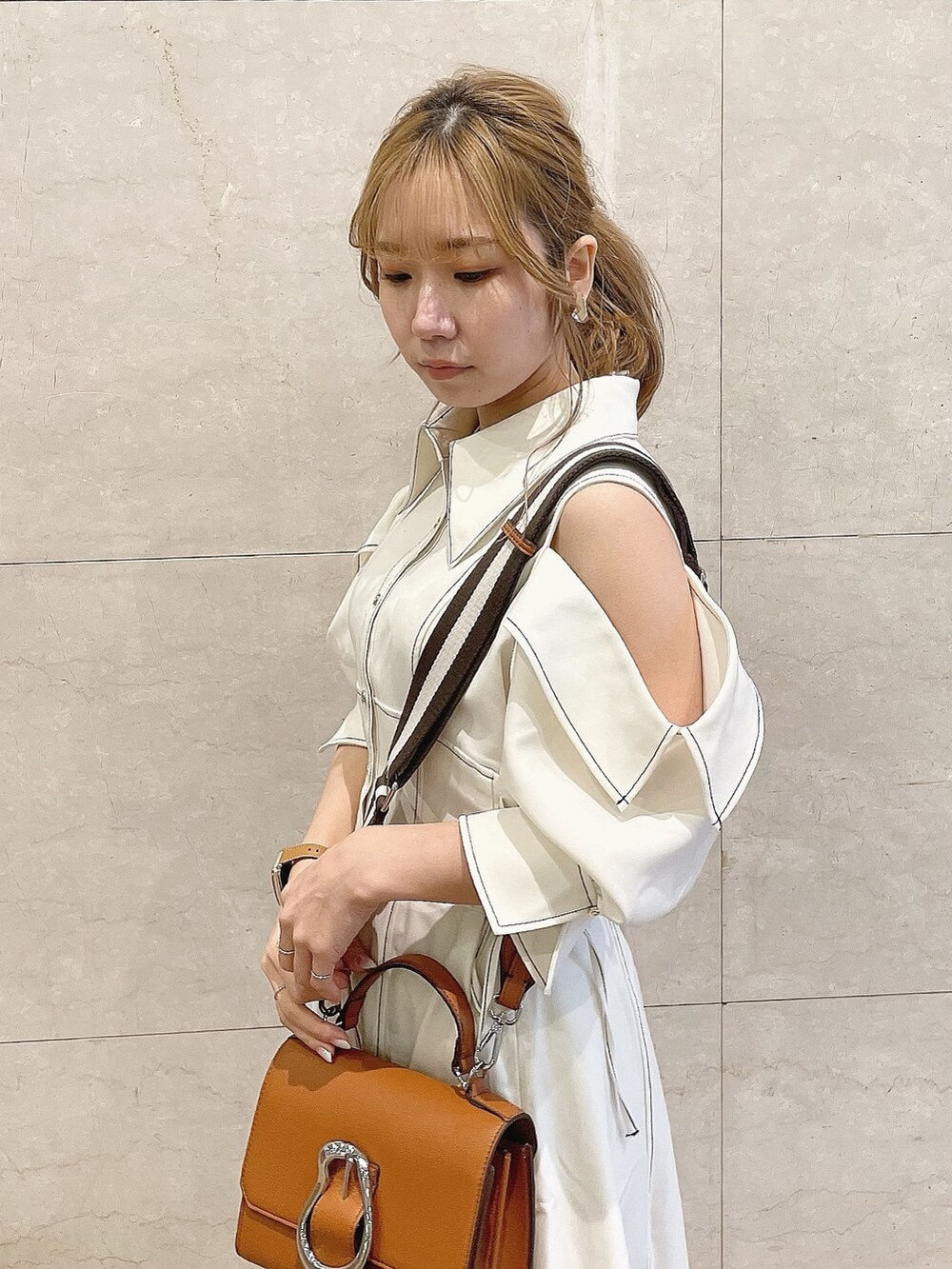 ホワイト系のワンピース、ホワイト系のパンプス、イエロー系のハンドバッグを着用したレディースの冬コーディネートの6枚目の写真