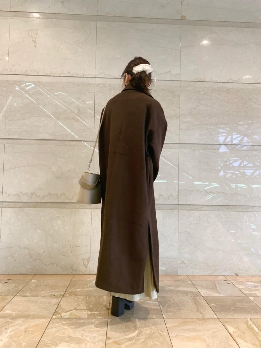 ブラック系のブーツ、ブラウン系のチェスターコート、ベージュ系のワンピースを着用したレディースの冬コーディネートの6枚目の写真