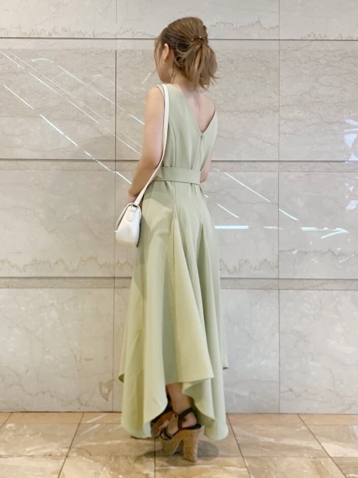 グリーン系のワンピース、ブラウン系のサンダル、ホワイト系のシャツ/ブラウスを着用したレディースの春コーディネートの2枚目の写真