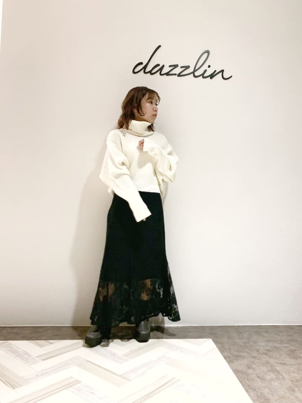 ブラック系のスカート、グレー系のブーツ、ホワイト系のニット/セーターを着用したレディースの秋コーディネートの2枚目の写真