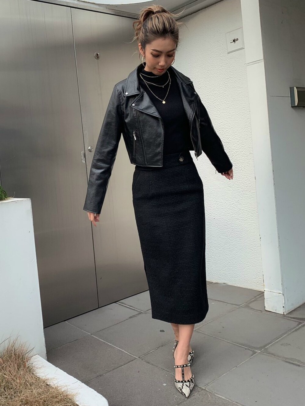 ブラック系のスカート、ブラック系のニット/セーター、ゴールド系のピアス（両耳用）を着用したレディースの冬コーディネートの4枚目の写真