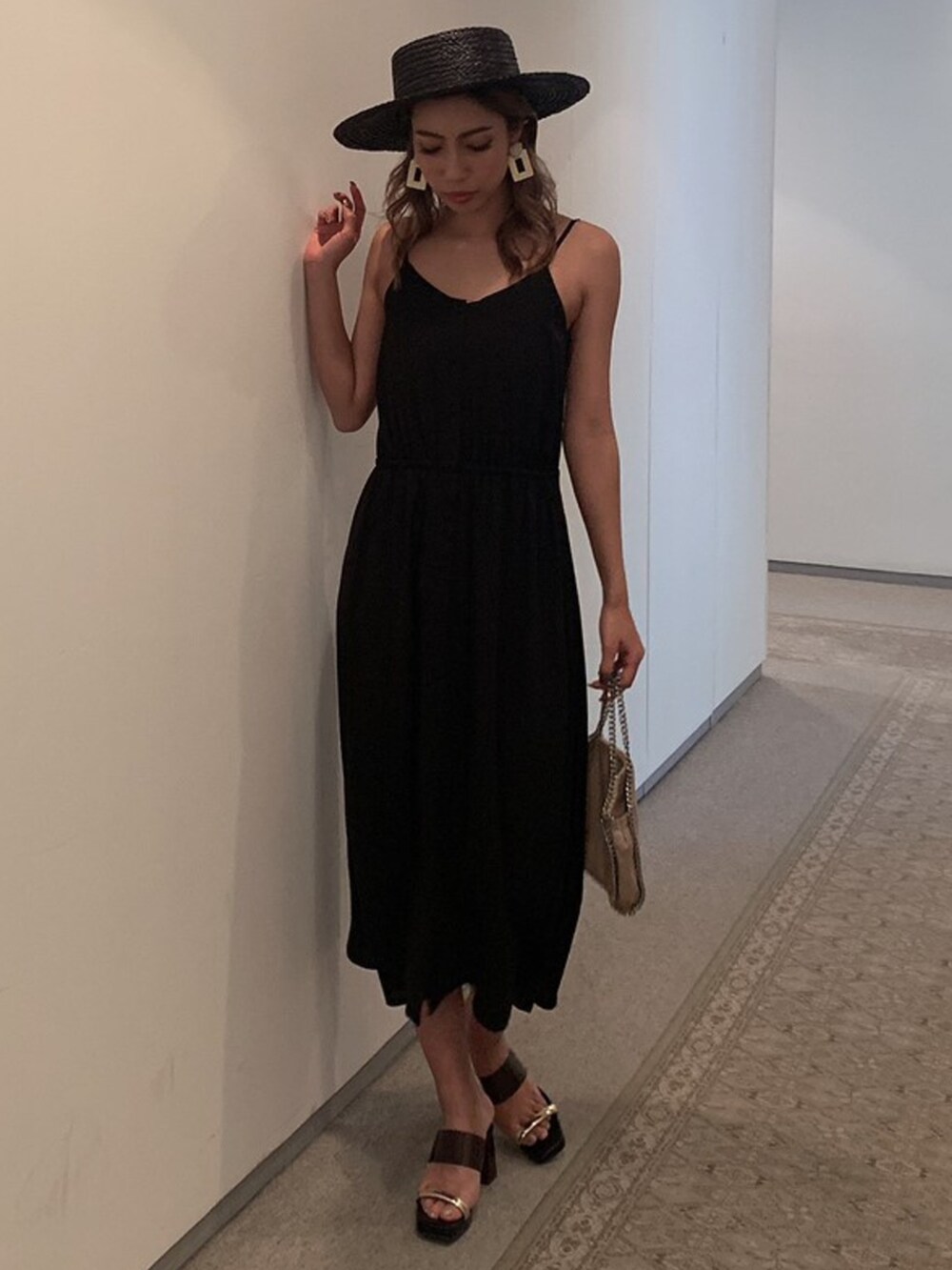 ブラック系のワンピース、ホワイト系のピアス（両耳用）、ブラック系のハットを着用したレディースの春コーディネートの2枚目の写真