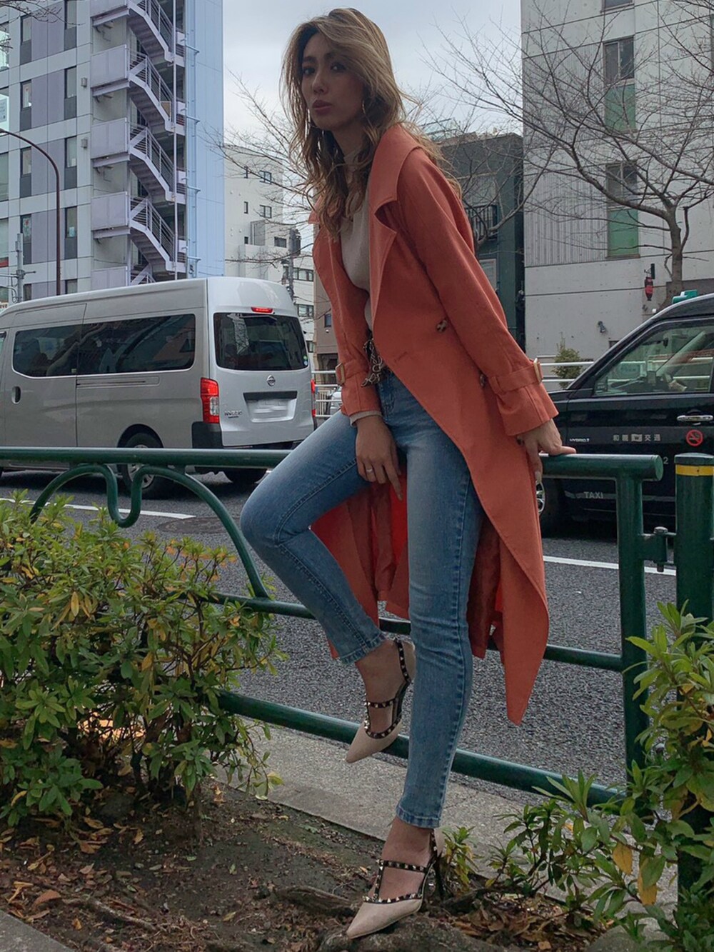 ピンク系のトレンチコート、ブルー系のデニムパンツを着用したレディースの冬コーディネートの2枚目の写真