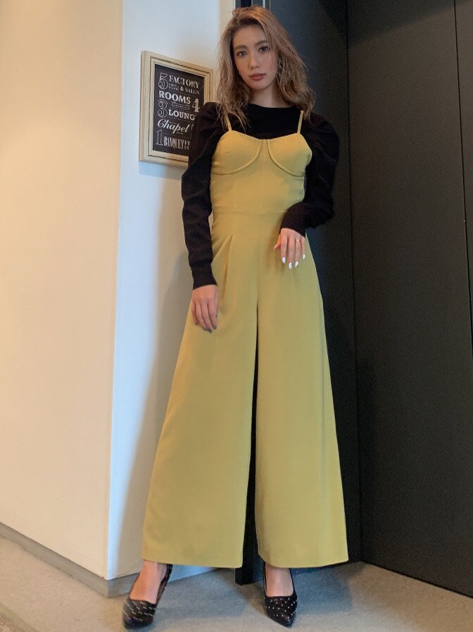 ブラック系のパンプス、ブラック系のニット/セーター、イエロー系のつなぎ/オールインワンを着用したレディースの秋コーディネートの2枚目の写真