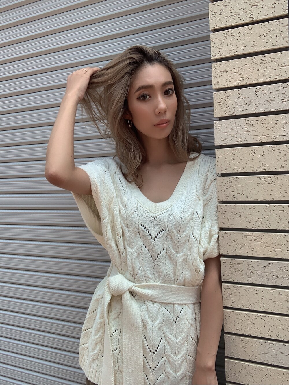 ベージュ系のスカート、ホワイト系のニット/セーター、ブラウン系のハンドバッグを着用したレディースの夏コーディネートの3枚目の写真