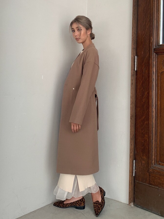 ベージュ系のノーカラーコート、ホワイト系のニット/セーター、ホワイト系のスカートを着用したレディースの秋コーディネートの2枚目の写真