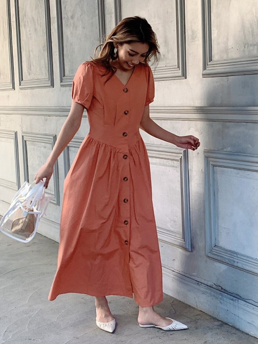 オレンジ系のワンピース、ホワイト系のハンドバッグを着用したレディースの春コーディネートの2枚目の写真