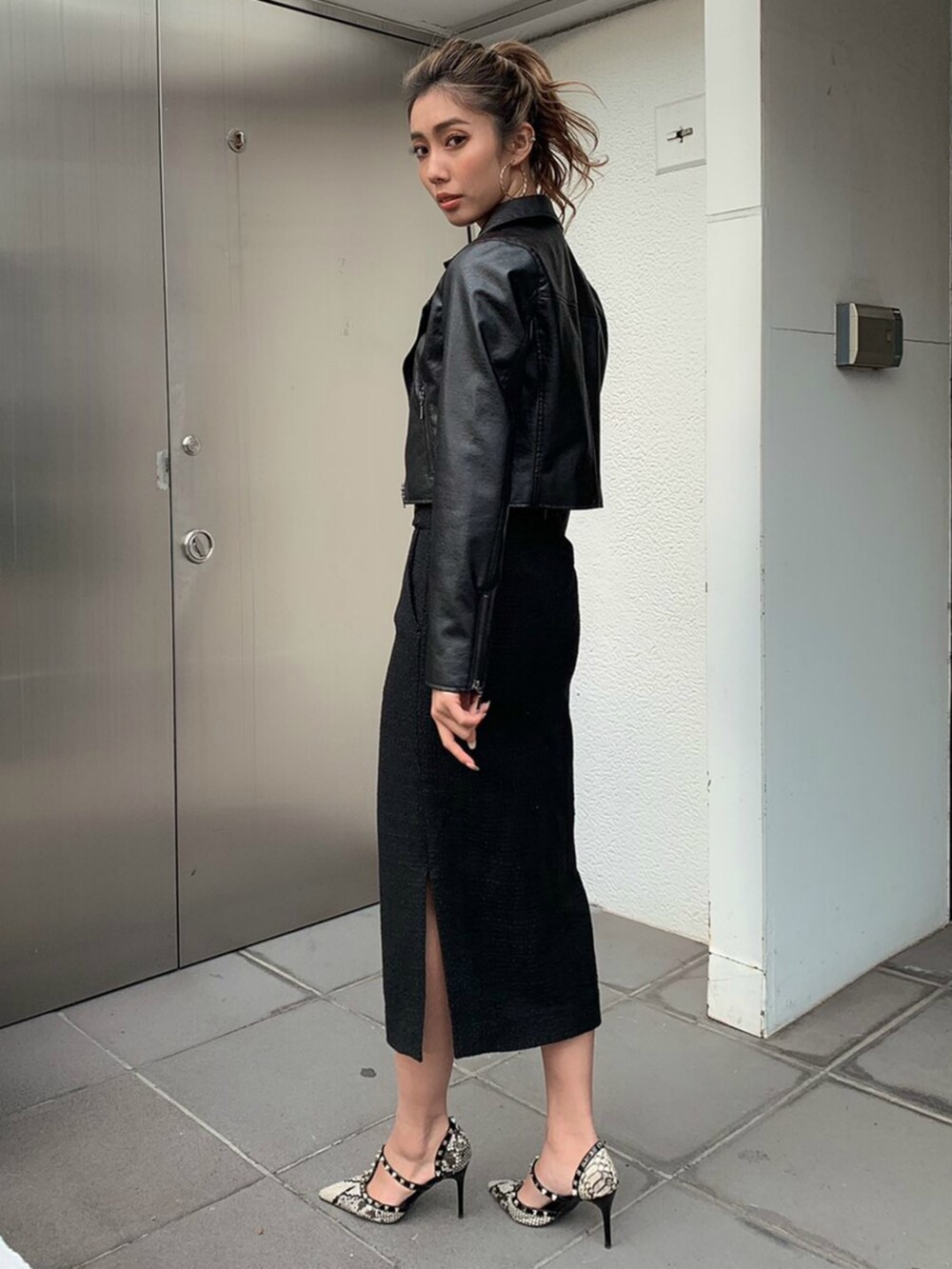 ブラック系のスカート、ブラック系のニット/セーター、ゴールド系のピアス（両耳用）を着用したレディースの冬コーディネートの3枚目の写真