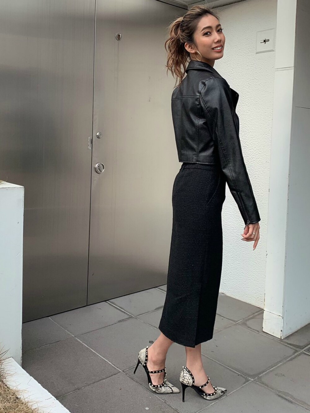 ブラック系のスカート、ブラック系のニット/セーター、ゴールド系のピアス（両耳用）を着用したレディースの冬コーディネートの2枚目の写真